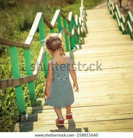 Little girl walking down stairs. View from the back.