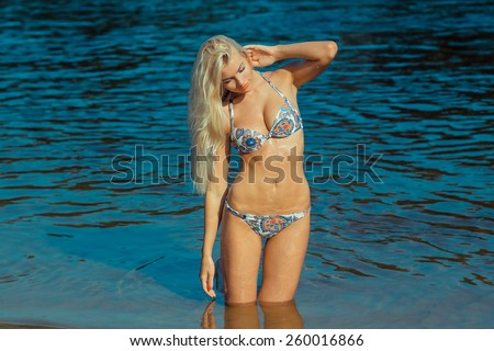 Beautiful young blond woman in a bikini on the beach near the sea