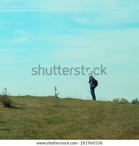 Elderly man travels in wildlife. Portrait of the gray-haired traveler in background of the landscape. Old photographer enjoys traveling and photography