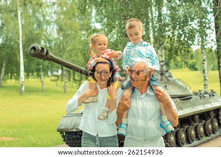 family of three generations having fun on the background of the historic vintage military vehicle. Family portrait of three generations on the background of military equipment