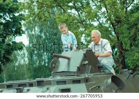 Grandfather and grandson explore military vintage historical transport. Grandfather and grandson at a military armored personnel carrier