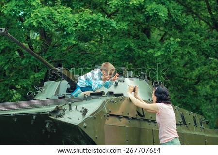 Mom takes pictures of his son on vintage military vehicle