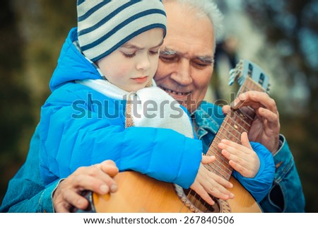 Grandfather and grandson playing guitar outdoors
