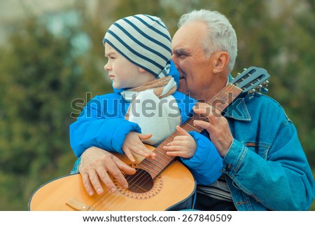 close-up of hands grandfather and grandson to play guitar. Grandfather and grandson playing guitar outdoors
