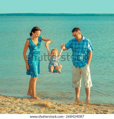View of happy young family having fun on the beach. happy young family in a blue dress have fun at vacations on beautiful beach