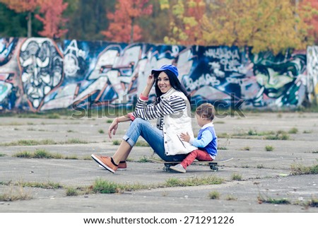 Mother and son on a skateboard. young mother teaches her little boy to ride a skateboard