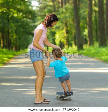 Mother and son on a skateboard. young mother teaches her little boy to ride a skateboard