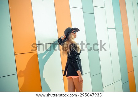 beautiful attractive trendy girl in long-skirted hat posing on the background orange wall
