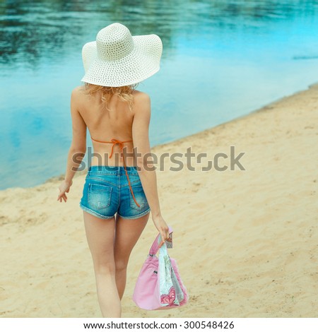 A girl in a swimsuit back. summer holidays concept - back view of beautiful woman in  and hat on a beach
