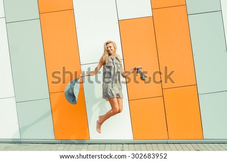 The girl catches the wind plucked the hat. Woman jumping joyfully with a hat