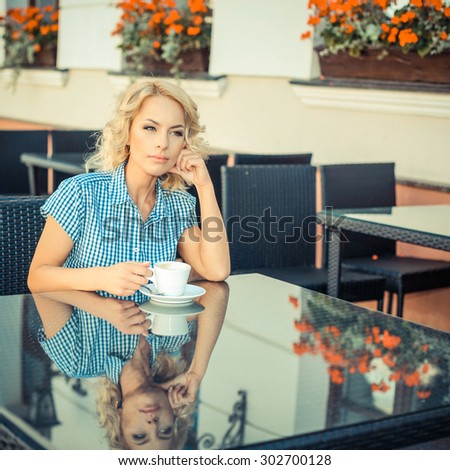 beautiful young girl resting in a cafe. attractive blond model sitting with a cup of coffee in an outdoor cafe of the European city