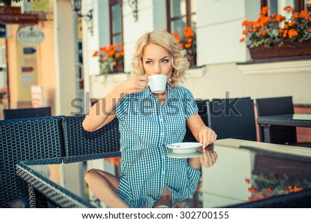 beautiful young girl resting in a cafe. attractive blond model sitting with a cup of coffee in an outdoor cafe of the European city