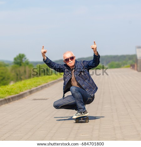 energetic senior man enjoying riding a skateboard. The concept of life satisfaction. Portrait of a positive gray-haired man with a skateboard. winner concept.
