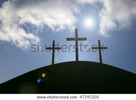 Three crosses on a grassy hill with sun-flare and clouds.