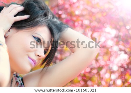 Girl posing with hands in hair and flowery pink and glamour background