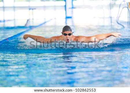 Man breathing while swimming  butterfly strokes in competition wearing swimming goggles and cap