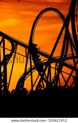 silhouette of a roller coaster at a purple sunset with people on the ride