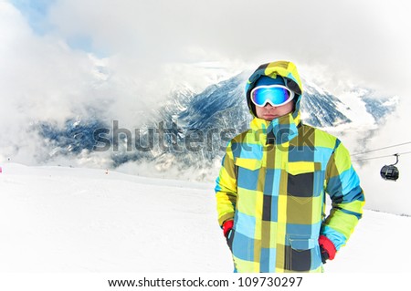 Young male wearing winter snowboarding costume on top of alpine mountains