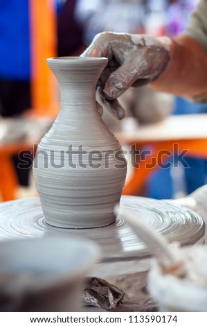 Hands of an old potter making a flower vase out of earth