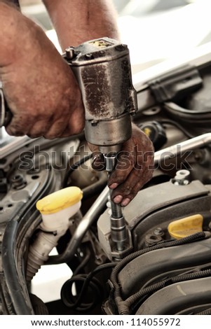 Mechanic using impact wrench for unscrewing engine components