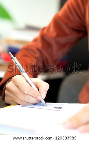 Young business woman writing a legal contract at the office, close-up of signature