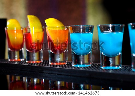 Several alcoholic shots of different drinks at a party in a nightclub on the counter