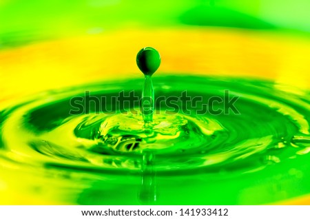 Green liquid paint drop splashing in yellow color