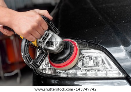 Car headlights cleaning with power buffer machine at car service