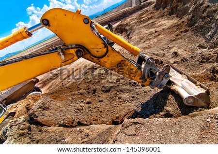 Excavator digging a hole and loading a dumper truck with soil in construction site