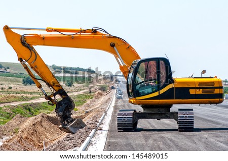 heavy duty excavator working in sand on the side of road construction site