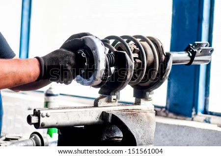 Auto mechanical engineer  adjusting a car shock absorber in car service workshop