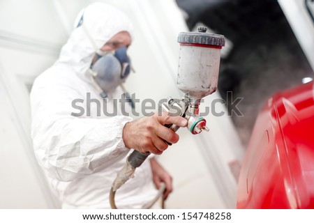 Auto painter spraying paint on a car body