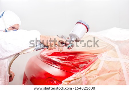 auto engineer painting a red paint on  car in special booth