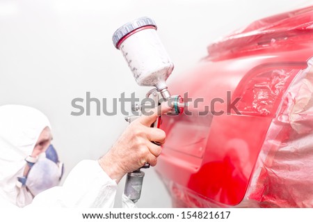auto engineer painting a red paint on modern car in special booth
