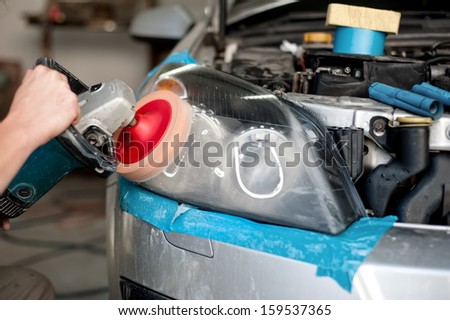 auto mechanic working on polishing a car headlight with power buffer machine in car care system