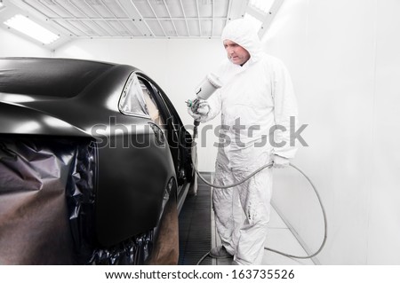 mechanical worker and engineer working on painting a black car in a painting booth