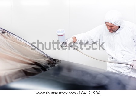 car painter working on a black car in a special painting booth. Automotive engineer concept