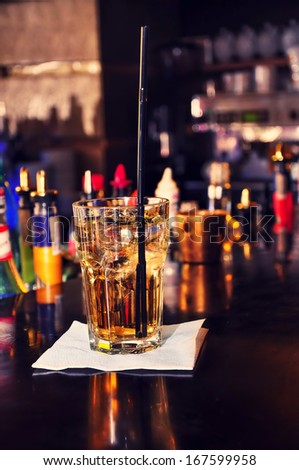 energetic alcoholic beverage on bar with straw and whiskey with  nightclub background