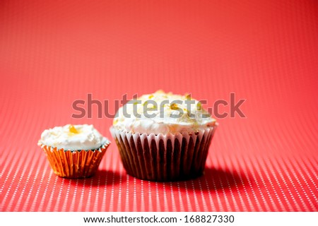one-bite small chocolate cupcake and normal size homemade chocolate cake against red dots background