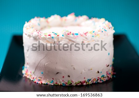 Creamy white chocolate and sweet birthday cake isolated on black plate and turquoise background