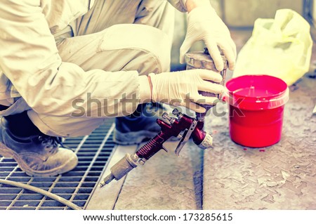 Industrial worker preparing red paint for spraying a car in painting booth