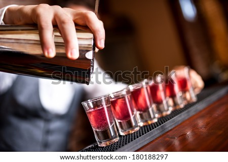 close-up of barman hand pouring alcohol into shot glasses in a nightclub or bar