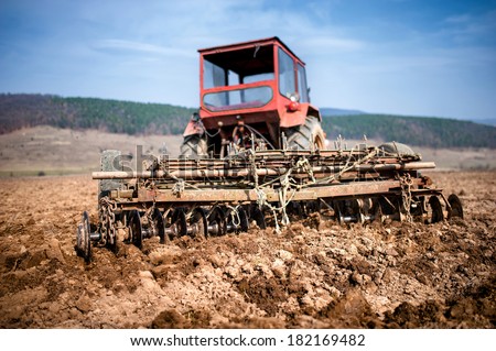 Tractor at farm working and plowing the field. Agriculture and harvesting