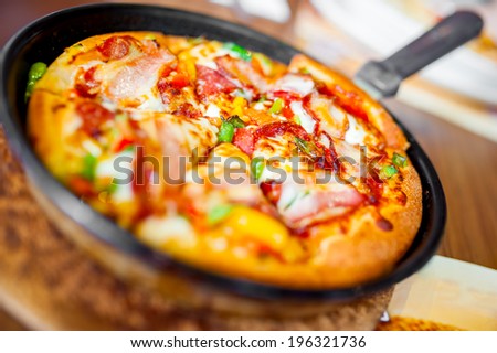 Close-up of hot pizza with fresh ingredients and vegetables served on hot plate