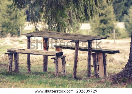 Vintage photo of a Wooden, rustic bench and picnic table, in the forest
