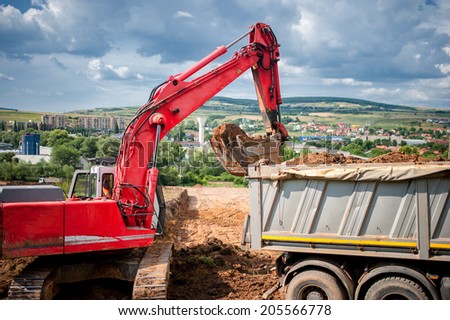 industrial excavator loader with raised backhoe standing in sandpit and digging in pit