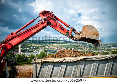 close-up of industrial excavator loading a dumper truck with soil and earth from construction site