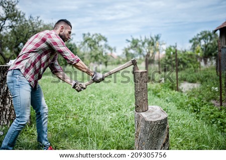 athletic man splitting wood and cutting firewood with axe