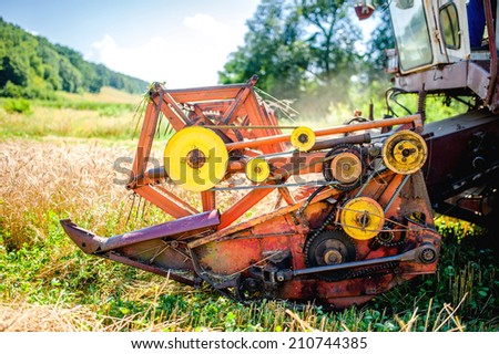 Detail of harvester machinery, tractor at farm with combine collecting mature grain crops