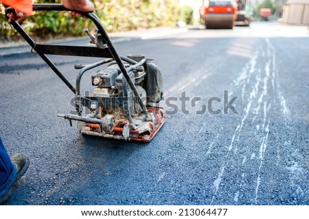 road construction with worker paving the fresh bitumen or asphalt